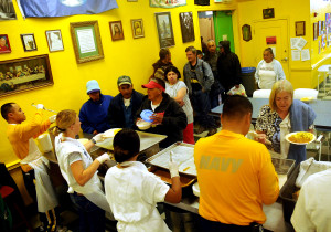 Volunteers at a soup kitchen serve food to homeless persons.