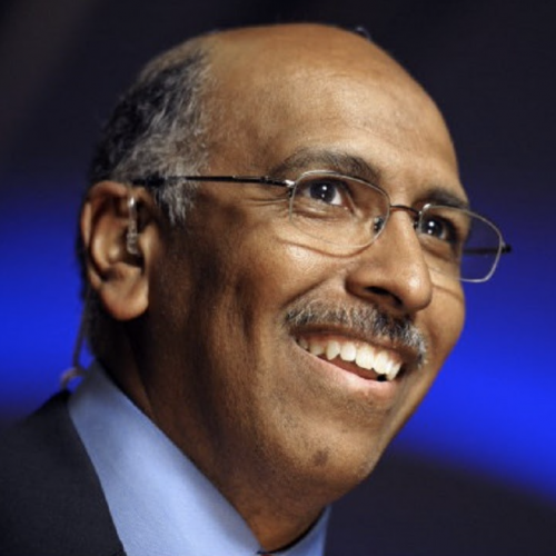 Black man with glasses, mustache, blue collared shirt, navy blue blazer, smiling